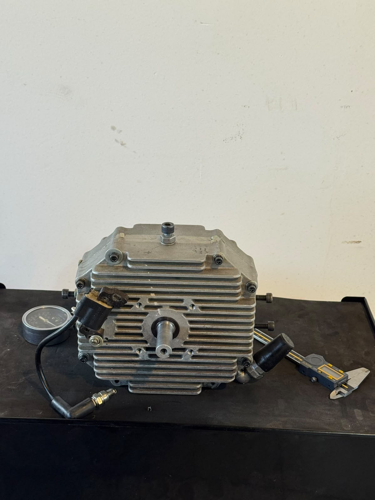 Front view of the bare Engine Core showing the output shaft, spark plug lead and measurement tools